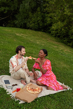 Couple enjoys pizza together on a picnic blanket