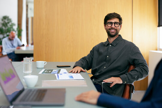 Smiling Businessman at Office Meeting Table