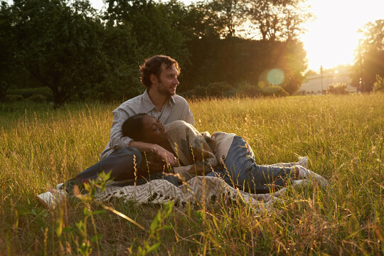 Couple relaxes on blanket during sunset in a field