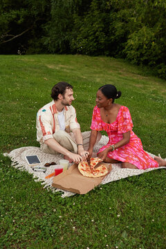 Couple sharing pizza on a blanket in a grassy park