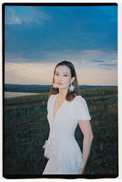 Portrait of a Young Woman in White Dress by the Lake at Sunset