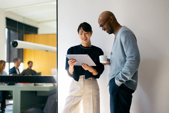 Businessman and Businesswoman Reviewing Documents on a Tablet