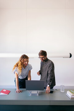 Businessman and Businesswoman Collaborating Over Laptop at Office