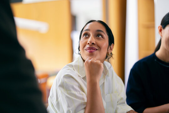 Thoughtful Young Woman Smiling During Office Team Meeting