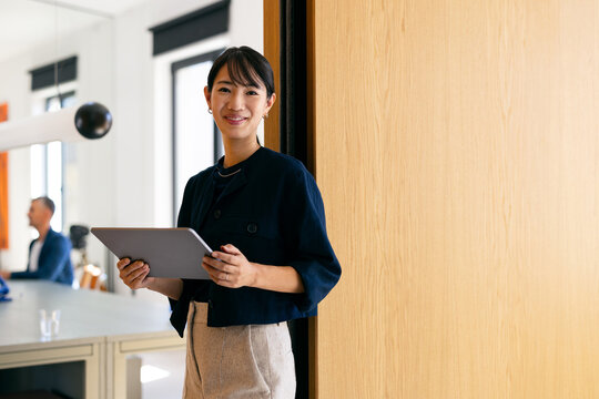 Smiling Businesswoman Holding Tablet in Modern Office