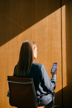 Businesswoman Checking Mobile Phone in Sunlit Office