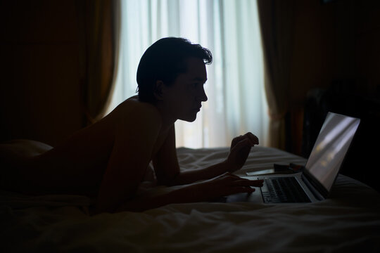Person Using a Laptop in a Bedroom During Evening Hours