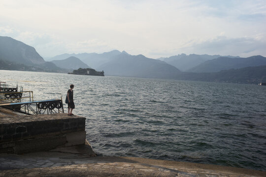 Person Walking Near Water With Mountains in Background