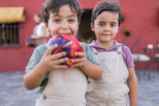 Two young siblings playing together with a ball in the home garden