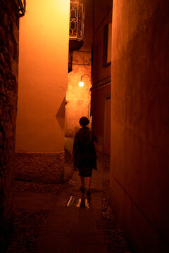 Woman Walking Alone in a Narrow Street at Night in a City