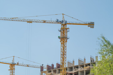 Bright blue sky showcases towering construction cranes above a bustling construction site highlighting progress and teamwork in a vibrant urban setting © beholdereye
