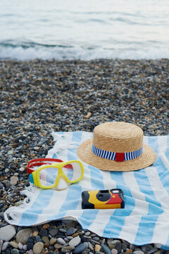 Disposable camera, straw hat and snorkeling mask on a towel