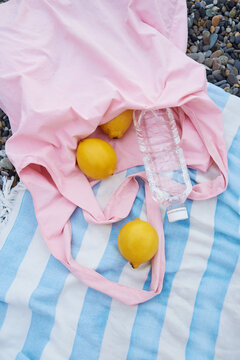 Beach towel with pink bag, lemons and bottle of water