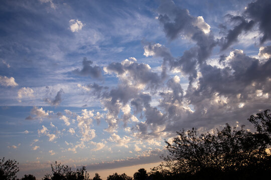 Sunset in the clouds. Dynamic blue sky with a contrasting mix of light cirrus and thick cumulus clouds that let in sunlight.