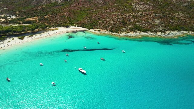 Saleccia white sand beach and yachts aerial cinematic footage. Agriates desert tropical bay, Caribbean of Europe Corsica with turquoise sea anchorage luxury boats, Plage de Saleccia drone 4K