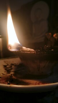Traditional Clay Oil Lamp Burning Brightly in Front of Buddha Statue, Cinematic 4K