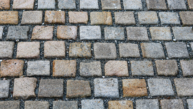 Closeup view of cobblestone pavement ground texture with square stone blocks in pattern.