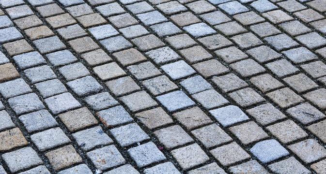 Cobblestone pavement ground texture with square stone blocks in pattern.