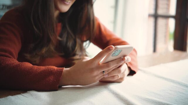 Close-up of an anonymous woman&rsquo;s hands using a smartphone at home, highlighting digital communication, mobile technology, everyday connectivity, and modern lifestyle.

