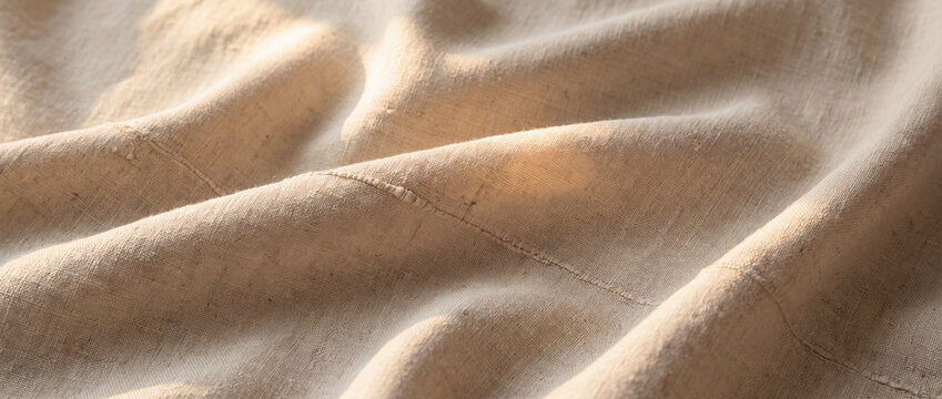 Beige linen fabric with stitched seam and warm sunlight