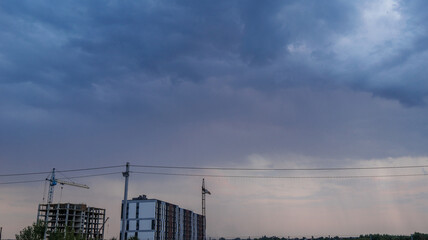 Fototapeta premium Construction site with cranes under a dramatic cloudy sky at dusk