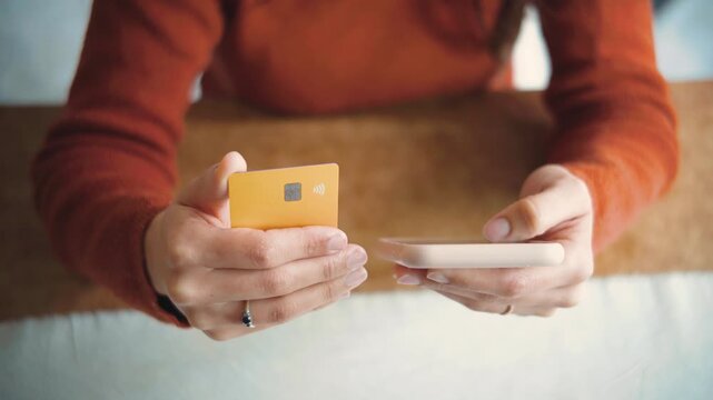 Close-up of an anonymous woman&rsquo;s hands making an online purchase with a credit card, highlighting ecommerce, digital payments, consumer spending, and modern shopping.
