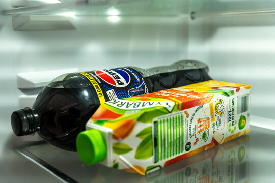 Warsaw, Poland - Sep 5, 2026: Pepsi bottle and Kubus juice carton lying on a refrigerator shelf in a home kitchen