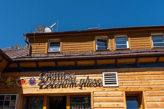 Vysoke Tatry, Slovakia - Aug 16, 2026: Wooden facade of the Chata pri Zelenom plese mountain hut with signage and solar panels under a clear blue sky