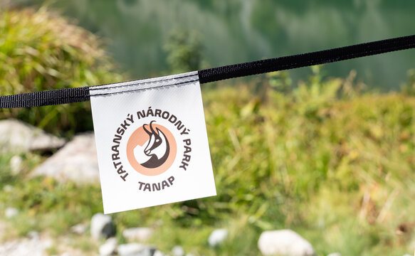 Vysoke Tatry, Slovakia - Aug 16, 2026: TANAP protected area marker tag hanging on a barrier rope beside alpine vegetation in the High Tatras