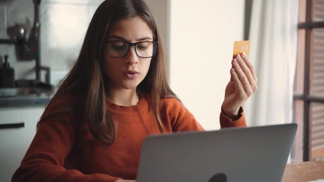 Young Latina woman using her laptop at home while shopping online, highlighting e-commerce, digital purchasing, consumer behavior, and modern home lifestyle.
