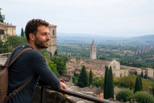 Panoramablick &uuml;ber Umbrien &ndash; Ein junger Reisender mit Rucksack genie&szlig;t von einer Aussichtsterrasse den Blick &uuml;ber eine historische H&uuml;gelstadt und die gr&uuml;ne Landschaft Mittelitaliens.