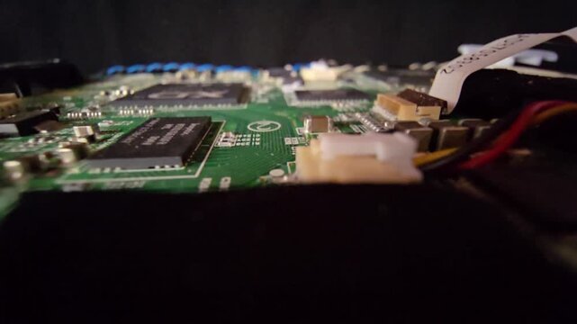 Low-angle perspective of a circuit board showing integrated circuit chip, flat ribbon cable, and surface components.