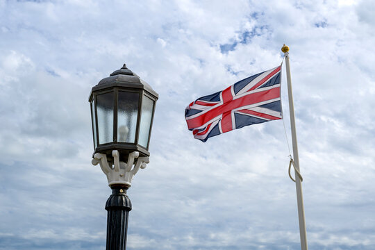 Union Jack Flag Flying Beside a Vintage Lamp