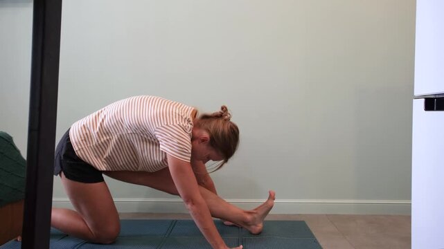 Mourning routines. middle adult woman training at small apartment in narrow corridor sitting on training mat