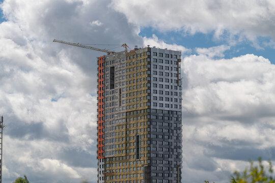 Skyline reshaped by modern architecture as a tall building nears completion in an urban landscape under fluffy clouds