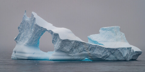 Iceberg arch emerging from Antarctic fog © Georg