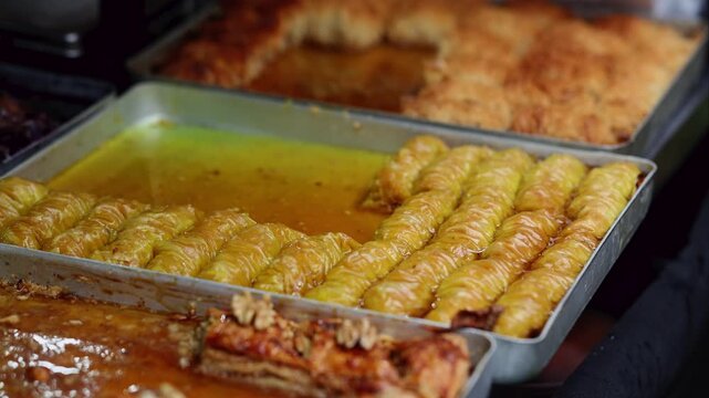 Trays of traditional baklava dessert soaked in honey syrup at oriental sweets market. Turkish pastry with nuts and phyllo dough. Middle eastern confectionery and street food concept.