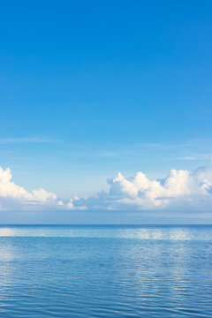 blue sea with clouds floating over the horizon