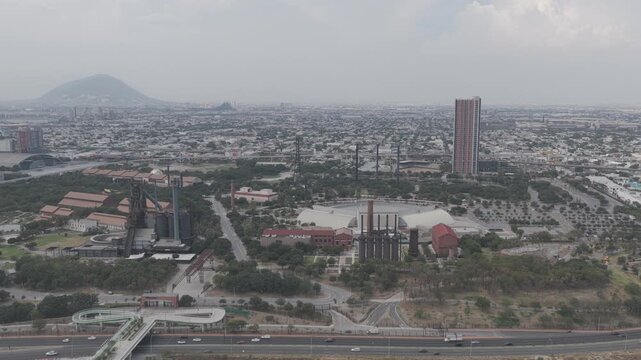 Aerial lateral tracking shot over Parque Fundidora in Monterrey with traffic moving along Avenida Constituci&oacute;n, Nuevo Le&oacute;n. D-Log M