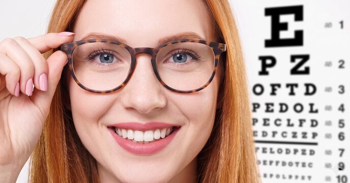 Woman with Glasses Smiling in Front of Eye Chart