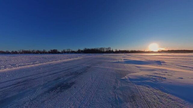 Driving plate pov on ice road on frozen lake Simcoe driving from Georgina Island to Virginia Wharf Beach during epic sunset. Seasonal ice higway crossing on frozen Lake Simcoe.