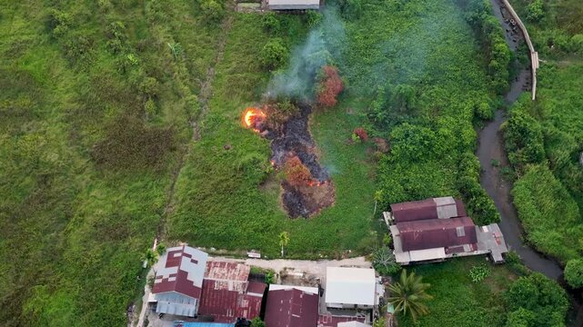 Small grass fire burning on land near houses in South Kalimantan Indonesia