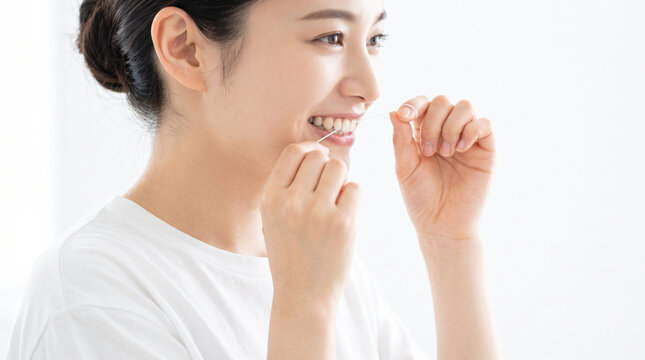 デンタルフロスを使って歯のセルフケアをする若い女性の笑顔