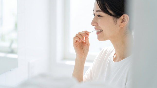 洗面台で歯間ブラシを使い丁寧に歯のケアをする女性
