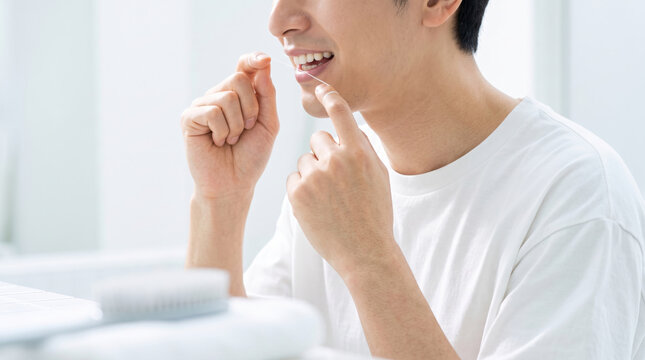 デンタルフロスを使って歯間ケアをする男性の口元