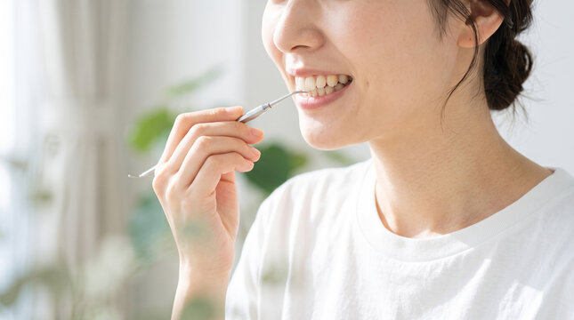 スケーラーを使って自分で歯石除去をする女性の口元
