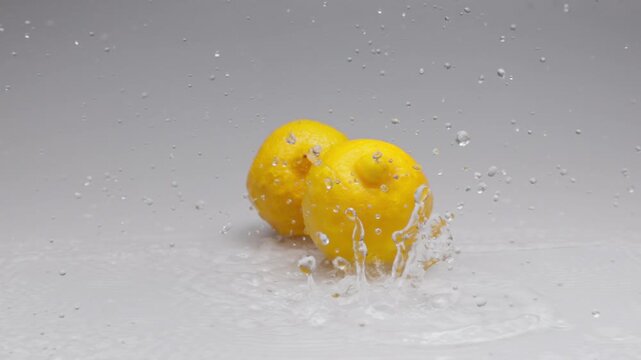 High speed slow motion of three whole lemons falling into water with explosive splashes on white. Fresh citrus food footage benefits beverage advertisements or organic product packaging as a design el