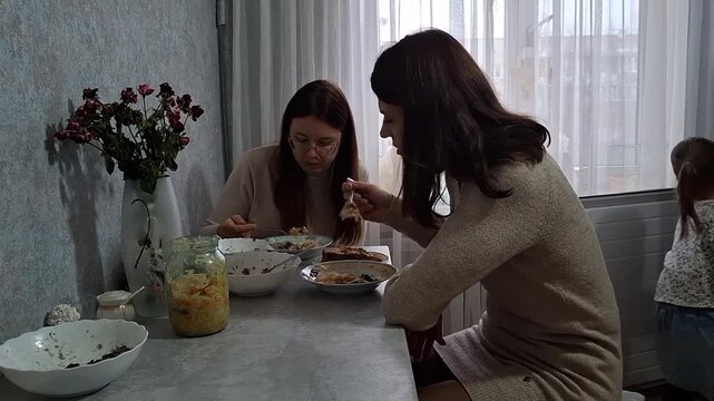Two women share a meal at home and enjoy conversation and food together during the day
