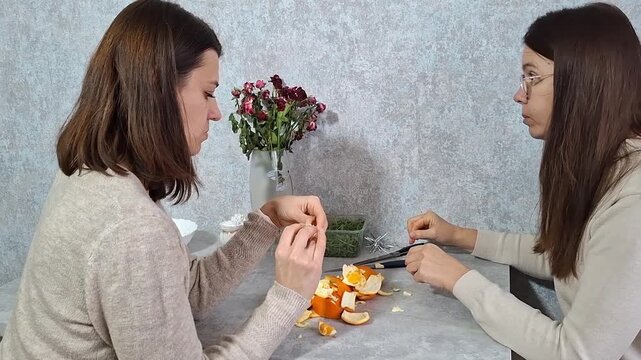 Two women preparing fruit for a project at a table in a kitchen