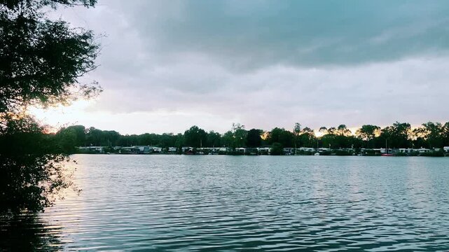 Sunset over the river with trees and cloudy sky in nature  